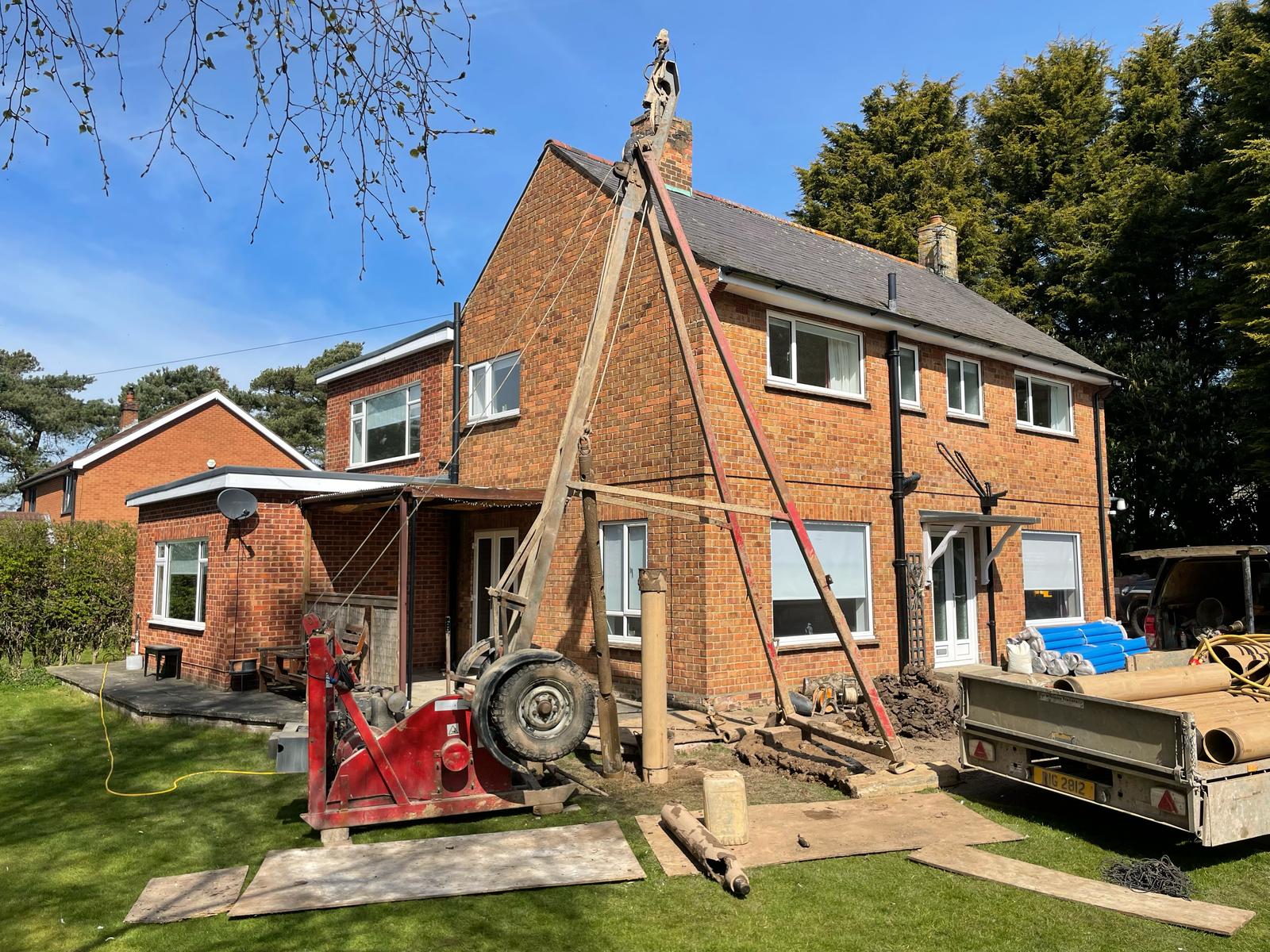 Borehole soakaway drilling rig and casing beside a residential property