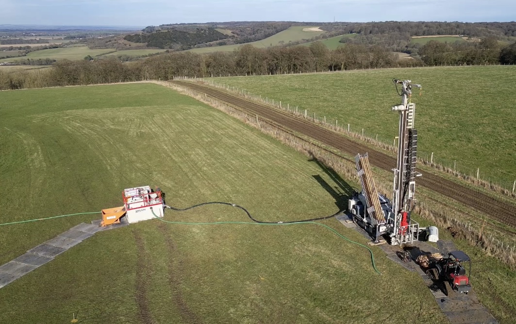 Ground-source borehole drilling rig in green countryside